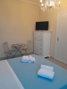 a bedroom with a bed with two towels and a tv at Lumera in Santa Flavia