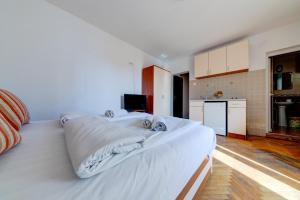 a large white bed in a room with a kitchen at Porta Volta Apartments in Becici