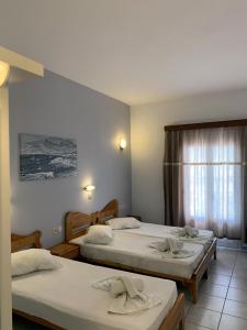 um quarto de hotel com três camas e uma janela em Hotel Aegeon em Mylopotas