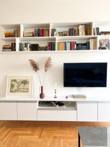 uma sala de estar branca com televisão e livros em Apartman Jelena em Trebinje