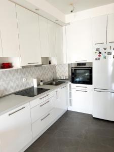 uma cozinha branca com armários e electrodomésticos brancos em Apartman Jelena em Trebinje