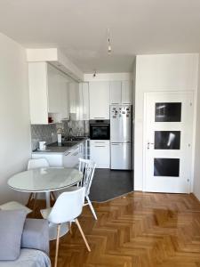 uma cozinha com armários brancos e uma mesa e cadeiras em Apartman Jelena em Trebinje