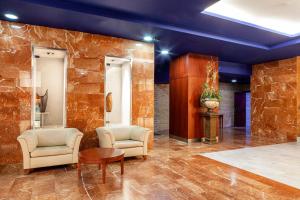 a lobby with two chairs and a stone wall at Hotel Olympia Valencia in Alboraya