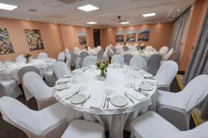 a conference room with white tables and white chairs at Casa Solada Hotel in Kampala