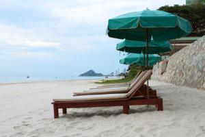 un grupo de sillas y sombrillas en una playa en Sailom Hotel Hua Hin - SHA Extra Plus en Hua Hin