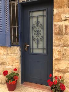eine blaue Tür mit roten Blumen und einem Fenster in der Unterkunft Lulia in Jerusalem