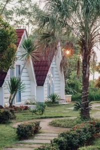 a white house with a red roof and a palm tree at Seaside Villa & Muse Beach Resto in Jepara