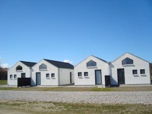 uma fila de casas brancas com telhados pretos em Slettestrandvej Apartment - Slettestrandvej 130 nr. 5 - ID 625 em Slettestrand