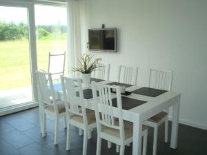 uma mesa de jantar branca com cadeiras brancas e uma televisão em Slettestrandvej Apartment - Slettestrandvej 130 nr. 5 - ID 625 em Slettestrand