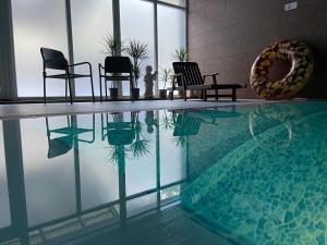 una piscina con sillas y un reflejo en el agua en Nidos kempingas, en Nida