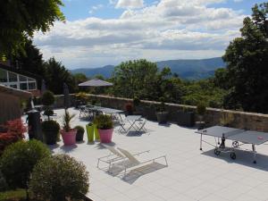 a patio with tables and chairs and mountains in the background at Maison d'Hotes Les Palmiers in Gluiras