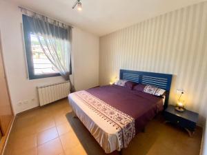 a bedroom with a bed with a purple bedspread and a window at Hauzify I Apartament Forques in Sant Feliu de Guíxols
