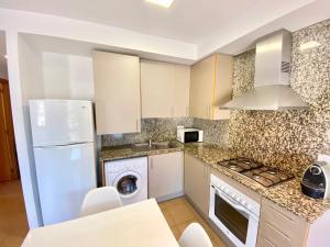 a kitchen with a white refrigerator and a dishwasher at Hauzify I Apartament Forques in Sant Feliu de Guíxols