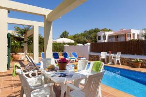 a patio with a table and chairs next to a pool at Villa Maggie by Villa Plus in Cala en Blanes