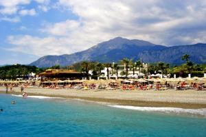 a beach with chairs and umbrellas and people in the water at Kemer Guney Homes Apart in Kemer