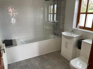 a white bathroom with a tub and a sink at The Loft at Duffryn Mawr Self Catering Cottages in Hensol +39 photos