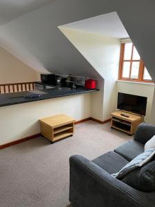 a attic living room with a couch and a television at The Loft at Duffryn Mawr Self Catering Cottages in Hensol