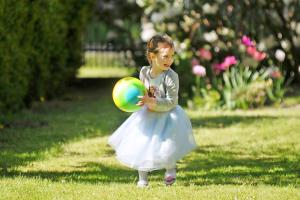 Una niña con un vestido blanco jugando con una pelota. en Relax en Kołobrzeg