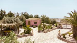 a garden with a pink house and some plants at Villa Vi in Ragusa