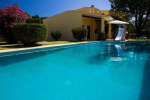 a large blue swimming pool in front of a house at Quinta Vita - Vila Limao in Almancil