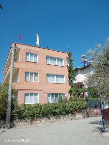 un alto edificio rosa con cespugli di fronte di HZD Apartments Hostel a Fethiye