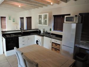 una cocina con armarios blancos y una mesa de madera. en 83 @ The Dunes, en Plettenberg Bay 8 fotos más