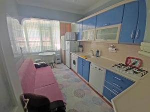 una pequeña cocina con armarios azules y un sofá rosa en GÜVEN PANSİYON, en Amasra