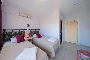two beds in a room with white walls and purple pillows at Casablanca Hotel in Dalyan
