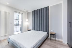 1 dormitorio con cama blanca y ventana en Apartments Browar Kleparz by Renters, en Cracovia
