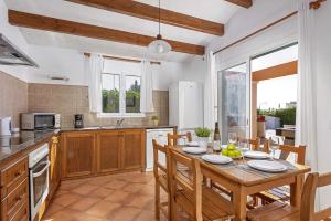 a kitchen with a wooden table and chairs and a kitchen with a dining room at Villa Violeta by Villa Plus in Cala en Bosc