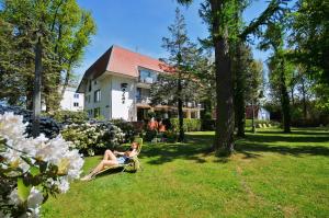 un homme assis sur une chaise dans la cour d'une maison dans l'établissement Relax, à Kołobrzeg