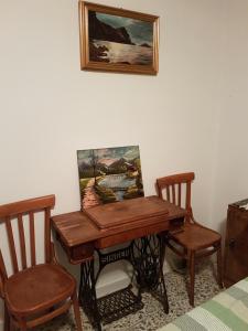 einen hölzernen Schreibtisch mit 2 Stühlen und ein Gemälde an der Wand in der Unterkunft Stanze private ARIANNA in Villanova Monteleone