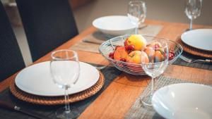 a table with a bowl of fruit and wine glasses at Gîte La Source in Grusse