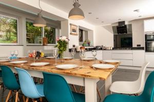 a kitchen with a large wooden table and blue chairs at Coastal Retreat in Woolacombe