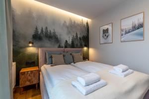 um quarto com uma grande cama branca com toalhas em SZARY WILK Apartament Szczyrk em Szczyrk