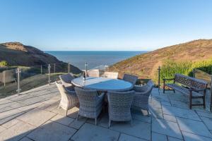 a patio with a table and chairs and the ocean at Heatherdale in Mortehoe