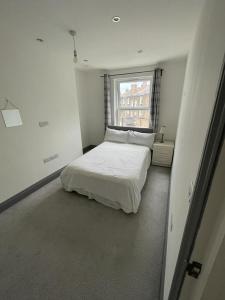 a white bedroom with a bed and a window at NKY CLASSIC BRIXTON APARTMENT Three in London