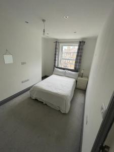 a white bedroom with a bed and a window at NKY CLASSIC BRIXTON APARTMENT Three in London