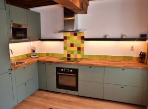 een keuken met groene en witte kasten en een fornuis bij Chez Daniel in Vauclaix