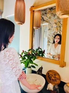 Que Toi Village Resort Phu Yen في Song Cau: امرأة تقف أمام مرآة