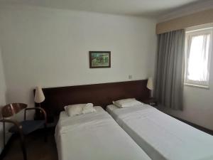 ein Hotelzimmer mit 2 Betten und einem Fenster in der Unterkunft Hot Water Guest House in Termas de Sao Pedro do Sul