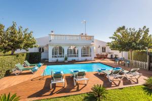 ein Swimmingpool mit Stühlen und ein Haus in der Unterkunft Villa Vera by Villa Plus in Cala'n Bosch