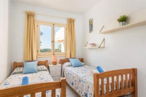 ein Schlafzimmer mit zwei Betten und einem Fenster in der Unterkunft Villa Vera by Villa Plus in Cala'n Bosch