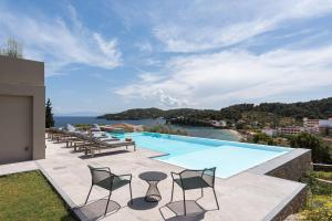 a swimming pool with chairs and a view of the ocean at Pelagoon Skiathos in Achladies