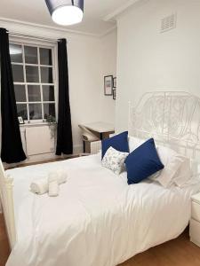 a white bed with blue pillows in a bedroom at Lovely 2 bed flat in SOHO! in London