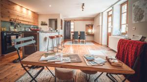 a room with a wooden table and a kitchen at Gîte La Source in Grusse