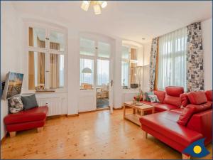 Ostseevilla Whg 02 في بانسين: غرفة معيشة مع أريكة حمراء وكراسي
