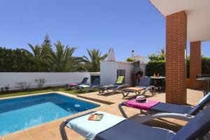a patio with a pool and chairs and a table at Villa Ondinas by Villa Plus in Cala en Forcat