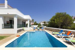 a swimming pool with chairs and a house at Villa Natasha by Villa Plus in Cala en Forcat