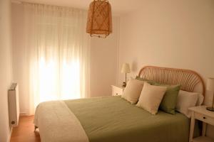 a bedroom with a green bed with a window at Arco da Vella apartamentos in Villanueva de Arosa